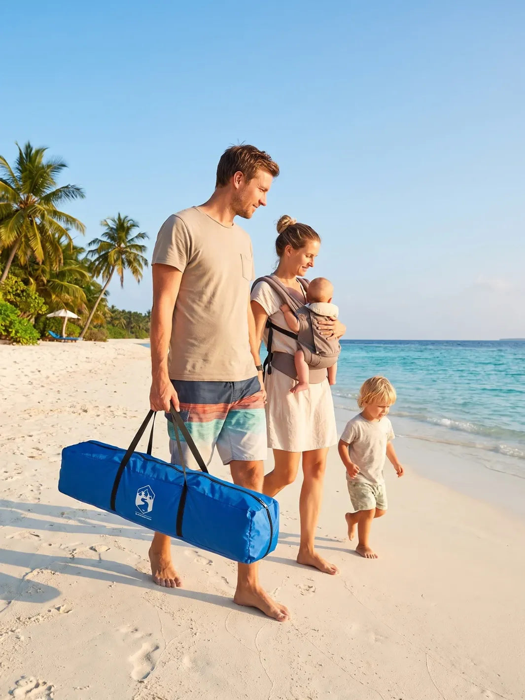 Famille portant la tente de plage 4 personnes dans son sac de transport en bord de mer